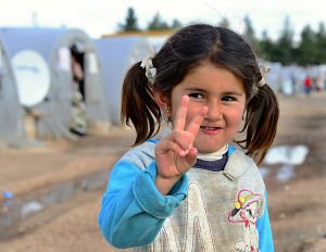 Smiling refugee girl showing the peace sign. © Radek Procyk | Dreamstime.com